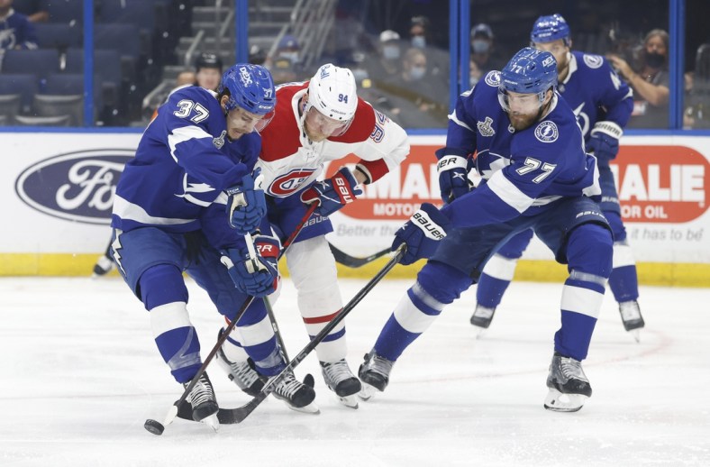 Jun 30, 2021; Tampa, Florida, USA;  Montreal Canadiens right wing Corey Perry (94) tries to get to the puck between Tampa Bay Lightning center Yanni Gourde (37) and defenseman Victor Hedman (77) during the first period in game two of the 2021 Stanley Cup Final at Amalie Arena. Mandatory Credit: Kim Klement-USA TODAY Sports