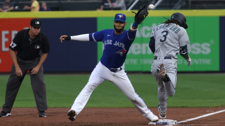 Jun 30, 2021; Buffalo, New York, USA; Seattle Mariners shortstop J.P. Crawford (3) is safe at first base as Toronto Blue Jays first baseman Lourdes Gurriel Jr. (center) misses the catch during the third inning at Sahlen Field. Mandatory Credit: Timothy T. Ludwig-USA TODAY Sports