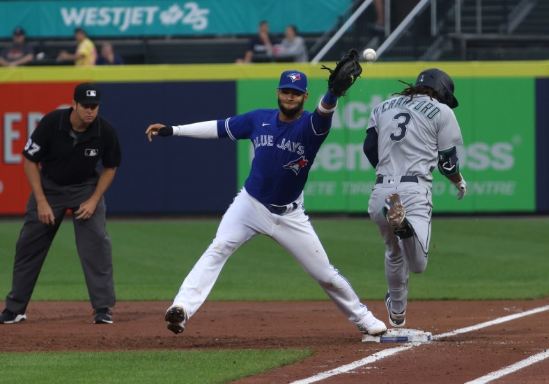 Jun 30, 2021; Buffalo, New York, USA; Seattle Mariners shortstop J.P. Crawford (3) is safe at first base as Toronto Blue Jays first baseman Lourdes Gurriel Jr. (center) misses the catch during the third inning at Sahlen Field. Mandatory Credit: Timothy T. Ludwig-USA TODAY Sports