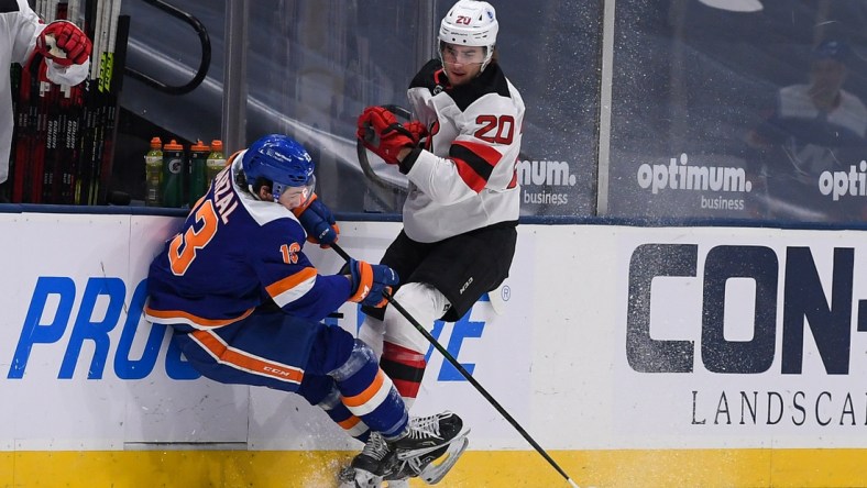 May 6, 2021; Uniondale, New York, USA;  New Jersey Devils center Michael McLeod (20) checks New York Islanders center Mathew Barzal (13) into the boards during the first period at Nassau Veterans Memorial Coliseum. Mandatory Credit: Dennis Schneidler-USA TODAY Sports