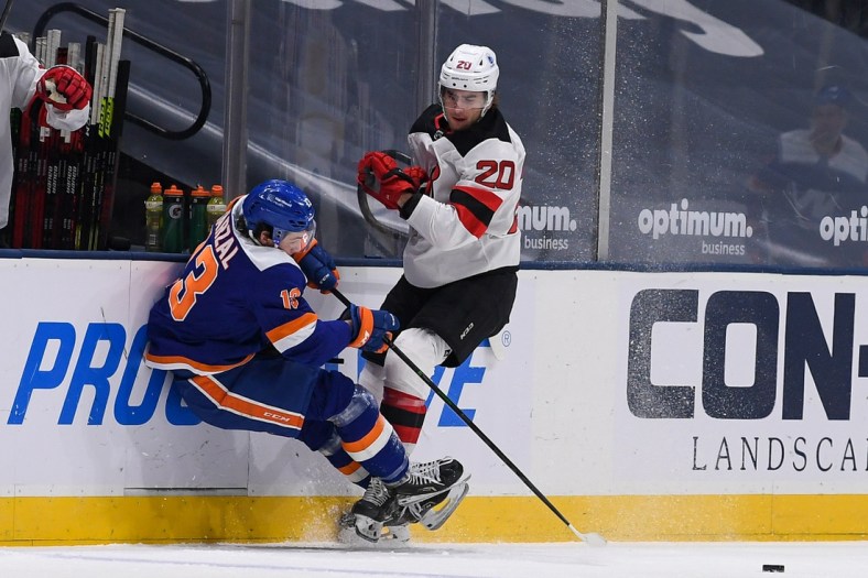 May 6, 2021; Uniondale, New York, USA;  New Jersey Devils center Michael McLeod (20) checks New York Islanders center Mathew Barzal (13) into the boards during the first period at Nassau Veterans Memorial Coliseum. Mandatory Credit: Dennis Schneidler-USA TODAY Sports