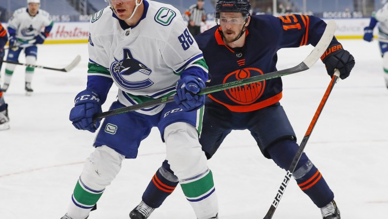 May 8, 2021; Edmonton, Alberta, CAN; Vancouver Canucks defensemen Nate Schmidt (88) and Edmonton Oilers forward Josh Archibald (15) chase a loose puck during the third period at Rogers Place. Mandatory Credit: Perry Nelson-USA TODAY Sports