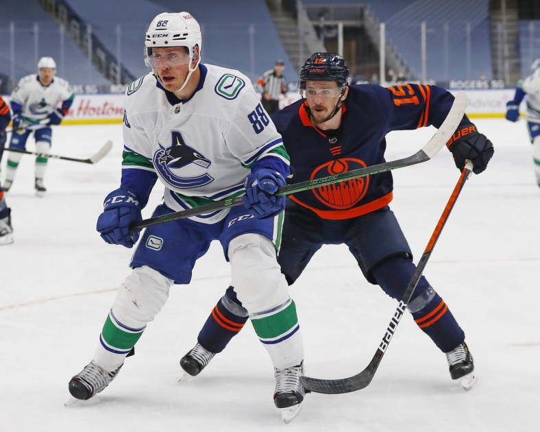 May 8, 2021; Edmonton, Alberta, CAN; Vancouver Canucks defensemen Nate Schmidt (88) and Edmonton Oilers forward Josh Archibald (15) chase a loose puck during the third period at Rogers Place. Mandatory Credit: Perry Nelson-USA TODAY Sports