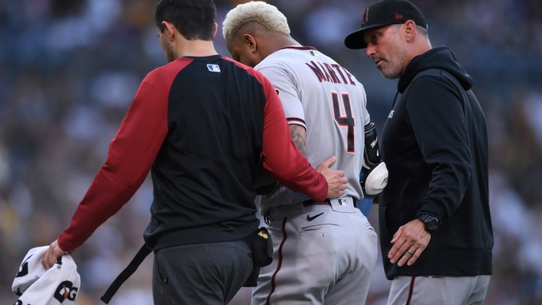 Jun 26, 2021; San Diego, California, USA; Arizona Diamondbacks center fielder Ketel Marte (4) is accompanied off the field by manager Torey Lovullo (right) after an injury during the first inning against the San Diego Padres at Petco Park. Mandatory Credit: Orlando Ramirez-USA TODAY Sports