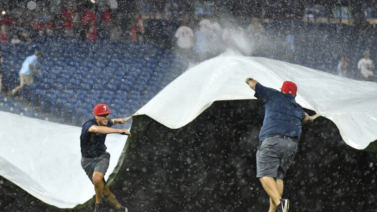 Jun 30, 2021; Philadelphia, Pennsylvania, USA; Members of the Philadelphia Phillies Grounds Crew pull the tarp over the infield during a rain delay in the fifth inning against the Miami Marlins at Citizens Bank Park. Mandatory Credit: Eric Hartline-USA TODAY Sports