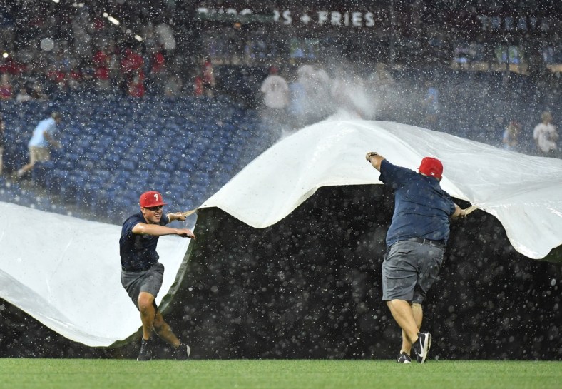 Jun 30, 2021; Philadelphia, Pennsylvania, USA; Members of the Philadelphia Phillies Grounds Crew pull the tarp over the infield during a rain delay in the fifth inning against the Miami Marlins at Citizens Bank Park. Mandatory Credit: Eric Hartline-USA TODAY Sports
