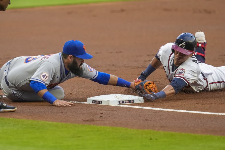 Jul 1, 2021; Cumberland, Georgia, USA; Atlanta Braves right fielder Ehire Adrianza (23) dives into third base against New York Mets third baseman Luis Guillorme (13) after hitting a triple during the first inning at Truist Park. Mandatory Credit: Dale Zanine-USA TODAY Sports