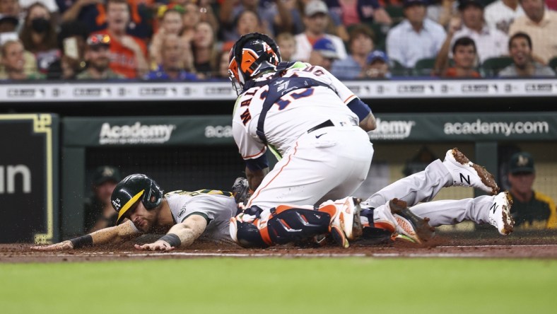 Jul 6, 2021; Houston, Texas, USA; Oakland Athletics left fielder Chad Pinder (4) is tagged out by Houston Astros catcher Martin Maldonado (15) at home plate during the first inning at Minute Maid Park. Mandatory Credit: Troy Taormina-USA TODAY Sports