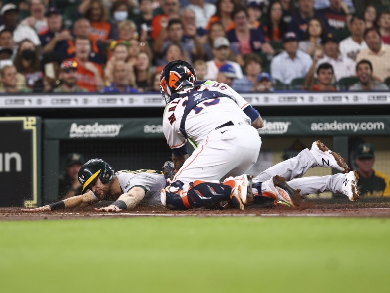 Jul 6, 2021; Houston, Texas, USA; Oakland Athletics left fielder Chad Pinder (4) is tagged out by Houston Astros catcher Martin Maldonado (15) at home plate during the first inning at Minute Maid Park. Mandatory Credit: Troy Taormina-USA TODAY Sports