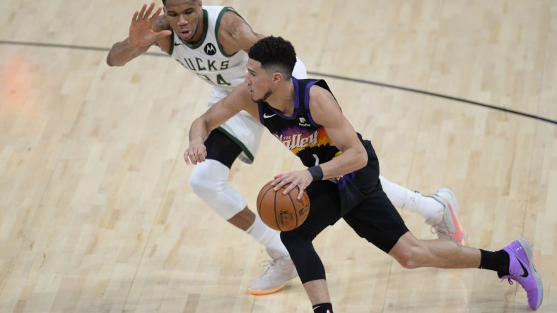 Jul 6, 2021; Phoenix, Arizona, USA; Phoenix Suns guard Devin Booker (1) moves the ball against Milwaukee Bucks forward Giannis Antetokounmpo (34) during the second half in game one of the 2021 NBA Finals at Phoenix Suns Arena. Mandatory Credit: Joe Camporeale-USA TODAY Sports