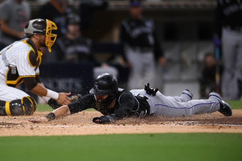 Jul 9, 2021; San Diego, California, USA; Colorado Rockies right fielder Chris Owings (right) slides home to score a run on a double hit by starting pitcher Kyle Freeland (not pictured) during the fourth inning against the San Diego Padres at Petco Park. Mandatory Credit: Orlando Ramirez-USA TODAY Sports