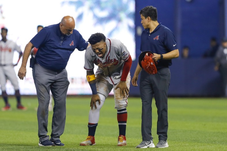 Jul 10, 2021; Miami, Florida, USA; Atlanta Braves right fielder Ronald Acuna Jr. (13) reacts as he gets check on by training staff after an apparent leg injury during the fifth inning  against the Miami Marlins at loanDepot Park. Mandatory Credit: Sam Navarro-USA TODAY Sports
