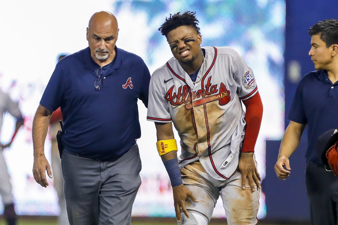 Jul 10, 2021; Miami, Florida, USA; Atlanta Braves right fielder Ronald Acuna Jr. (13) reacts as he gets taken off the field by training staff after an apparent leg injury during the fifth inning  against the Miami Marlins at loanDepot Park. Mandatory Credit: Sam Navarro-USA TODAY Sports