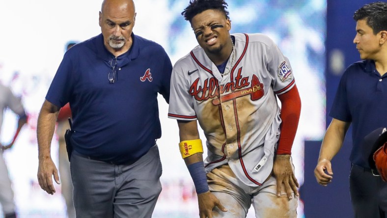 Jul 10, 2021; Miami, Florida, USA; Atlanta Braves right fielder Ronald Acuna Jr. (13) reacts as he gets taken off the field by training staff after an apparent leg injury during the fifth inning  against the Miami Marlins at loanDepot Park. Mandatory Credit: Sam Navarro-USA TODAY Sports