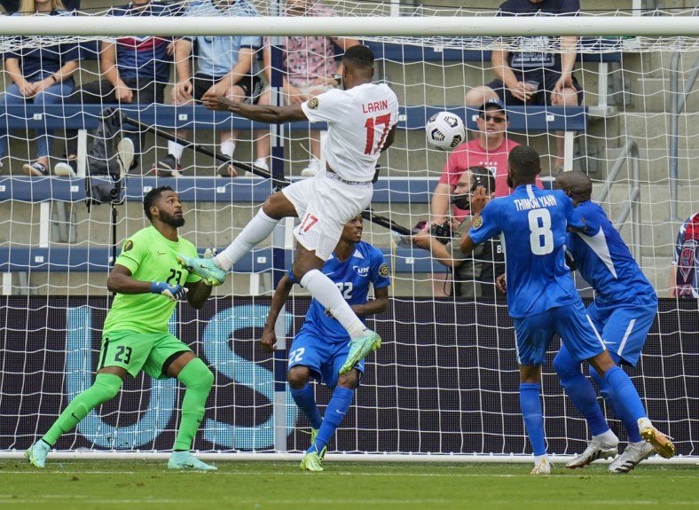 Jul 11, 2021; Kansas City, Kansas, USA; Canada forward Cyle Larin (17) scores a goal against Martinique goalkeeper Meslien Gilles (23) in the first half during a CONCACAF Gold Cup group stage soccer match at Children's Mercy Park. Mandatory Credit: Jay Biggerstaff-USA TODAY Sports