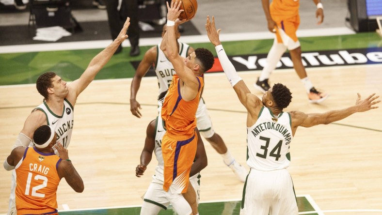 Jul 14, 2021; Milwaukee, Wisconsin, USA; Phoenix Suns guard Devin Booker (1) shoots between Milwaukee Bucks center Brook Lopez (11) and forward Giannis Antetokounmpo (34) during the third quarter during game four of the 2021 NBA Finals at Fiserv Forum. Mandatory Credit: Jeff Hanisch-USA TODAY Sports