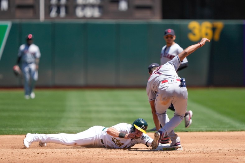 Jul 17, 2021; Oakland, California, USA;  Oakland Athletics left fielder Seth Brown (15) slides safely to second base during the second inning against Cleveland Indians shortstop Amed Rosario (1) at RingCentral Coliseum. Mandatory Credit: Stan Szeto-USA TODAY Sports