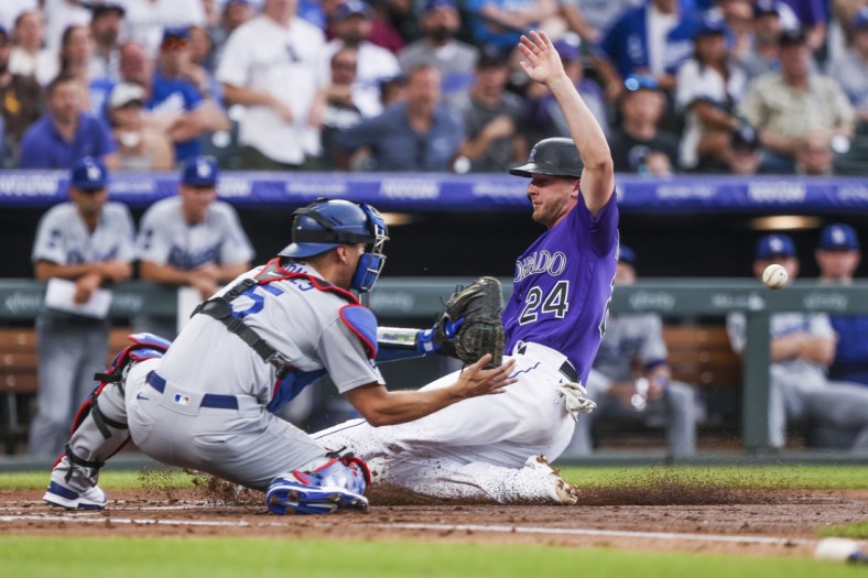 Jul 17, 2021; Denver, Colorado, USA; Colorado Rockies second baseman Ryan McMahon (24) slides past Los Angeles Dodgers catcher Austin Barnes (15) to score a run in the second inning at Coors Field. Mandatory Credit: Michael Ciaglo-USA TODAY Sports