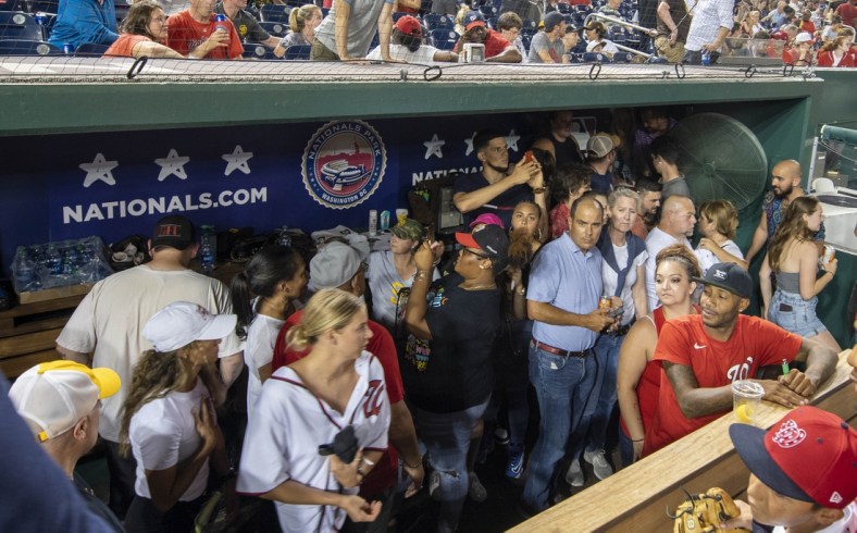 Jul 17, 2021; Washington, District of Columbia, USA; Fans take cover in Washington Nationals dugout after an apparent shooting outside Nationals Park during a game between the Washington Nationals and the San Diego Padres. Mandatory Credit: Brad Mills-USA TODAY Sports