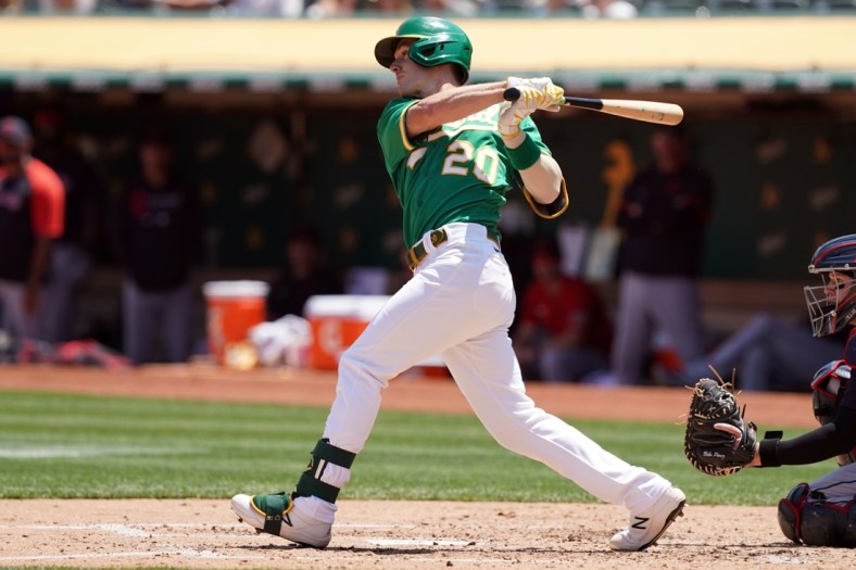 Jul 18, 2021; Oakland, California, USA; Oakland Athletics left fielder Mark Canha (20) hits a single during the third inning against the Cleveland Indians at RingCentral Coliseum. Mandatory Credit: Darren Yamashita-USA TODAY Sports