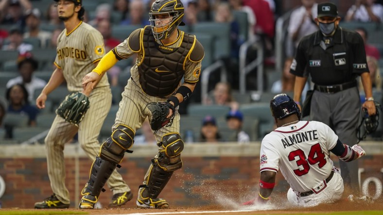 Jul 20, 2021; Cumberland, Georgia, USA; Atlanta Braves left fielder Abraham Almonte (34) scores a run behind San Diego Padres catcher Victor Caratini (17) during the second inning at Truist Park. Mandatory Credit: Dale Zanine-USA TODAY Sports