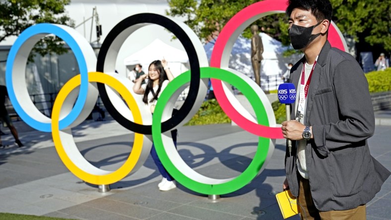 Jul 21, 2021; Tokyo, Japan; A reporter from KBS reports in front of the Olympic Rings outside the Olympic Stadium before the Tokyo 2020 Summer Olympic Games. Mandatory Credit: Michael Madrid-USA TODAY Network