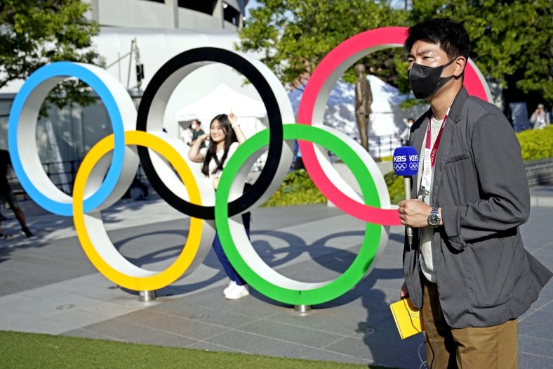 Jul 21, 2021; Tokyo, Japan; A reporter from KBS reports in front of the Olympic Rings outside the Olympic Stadium before the Tokyo 2020 Summer Olympic Games. Mandatory Credit: Michael Madrid-USA TODAY Network