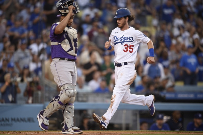 Jul 23, 2021; Los Angeles, California, USA; Los Angeles Dodgers center fielder Cody Bellinger (35) scores as Colorado Rockies catcher Elias Diaz (35) looks on during the first inning at Dodger Stadium. Mandatory Credit: Kelvin Kuo-USA TODAY Sports