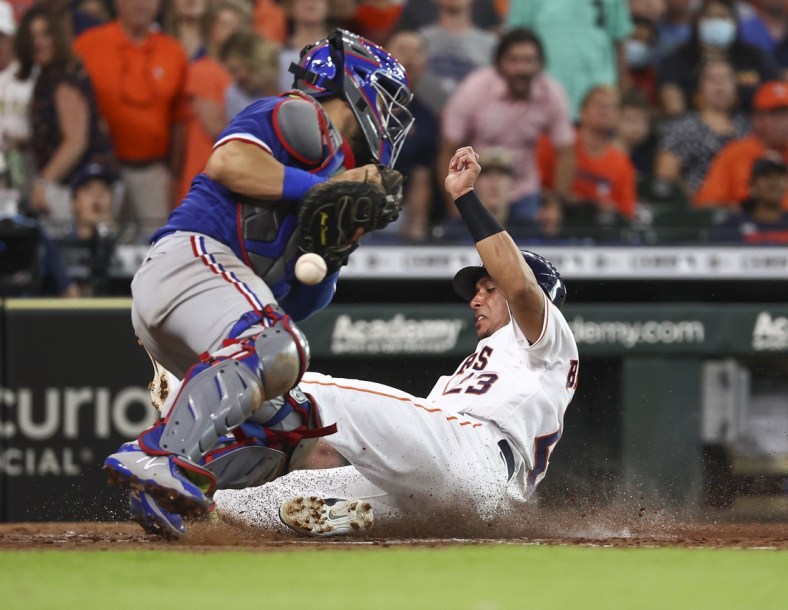 Jul 24, 2021; Houston, Texas, USA; Houston Astros designated hitter Michael Brantley (23) scores a run as Texas Rangers catcher Jose Trevino (23) attempts to field a throw during the third inning at Minute Maid Park. Mandatory Credit: Troy Taormina-USA TODAY Sports