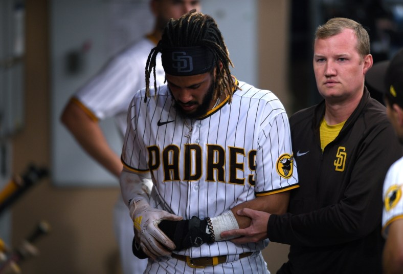 Jul 30, 2021; San Diego, California, USA; San Diego Padres shortstop Fernando Tatis Jr. (left) is helped through the dugout by a trainer after sustaining an injury during the first inning against the Colorado Rockies at Petco Park. Mandatory Credit: Orlando Ramirez-USA TODAY Sports