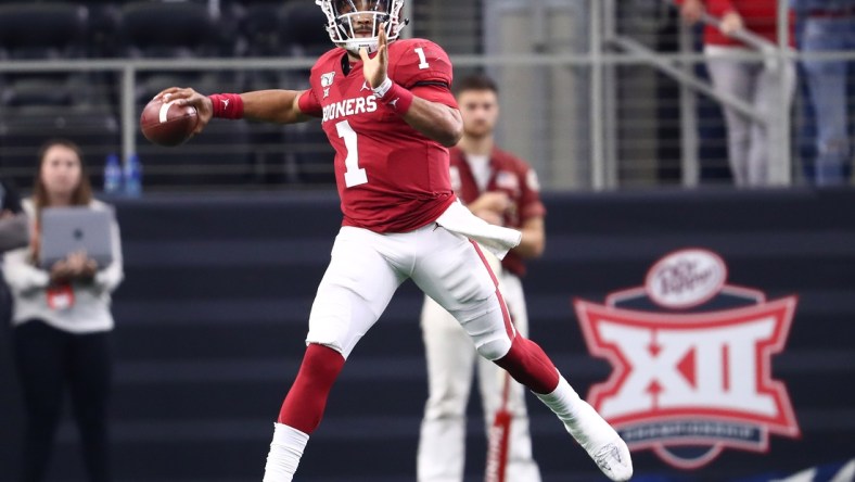 Dec 7, 2019; Arlington, TX, USA; Oklahoma Sooner quarterback Jalen Hurts (1) scrambles in front of the Big 12 logo during the second half against the Baylor Bears in the 2019 Big 12 Championship Game at AT&T Stadium. Mandatory Credit: Matthew Emmons-USA TODAY Sports