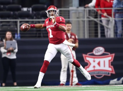 Dec 7, 2019; Arlington, TX, USA; Oklahoma Sooner quarterback Jalen Hurts (1) scrambles in front of the Big 12 logo during the second half against the Baylor Bears in the 2019 Big 12 Championship Game at AT&T Stadium. Mandatory Credit: Matthew Emmons-USA TODAY Sports