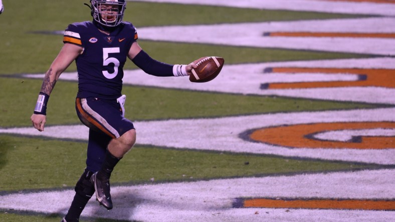 Nov 14, 2020; Charlottesville, Virginia, USA; Virginia Cavaliers quarterback Brennan Armstrong (5) celebrates after scoring a touchdown against the Louisville Cardinals in the fourth quarter at Scott Stadium. Mandatory Credit: Geoff Burke-USA TODAY Sports