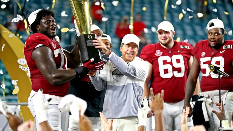 Jan 11, 2021; Miami Gardens, Florida, USA; Alabama Crimson Tide head coach Nick Saban and offensive lineman Alex Leatherwood (70) celebrates with the CFP National Championship trophy after beating the Ohio State Buckeyes in the 2021 College Football Playoff National Championship Game. Mandatory Credit: Mark J. Rebilas-USA TODAY Sports