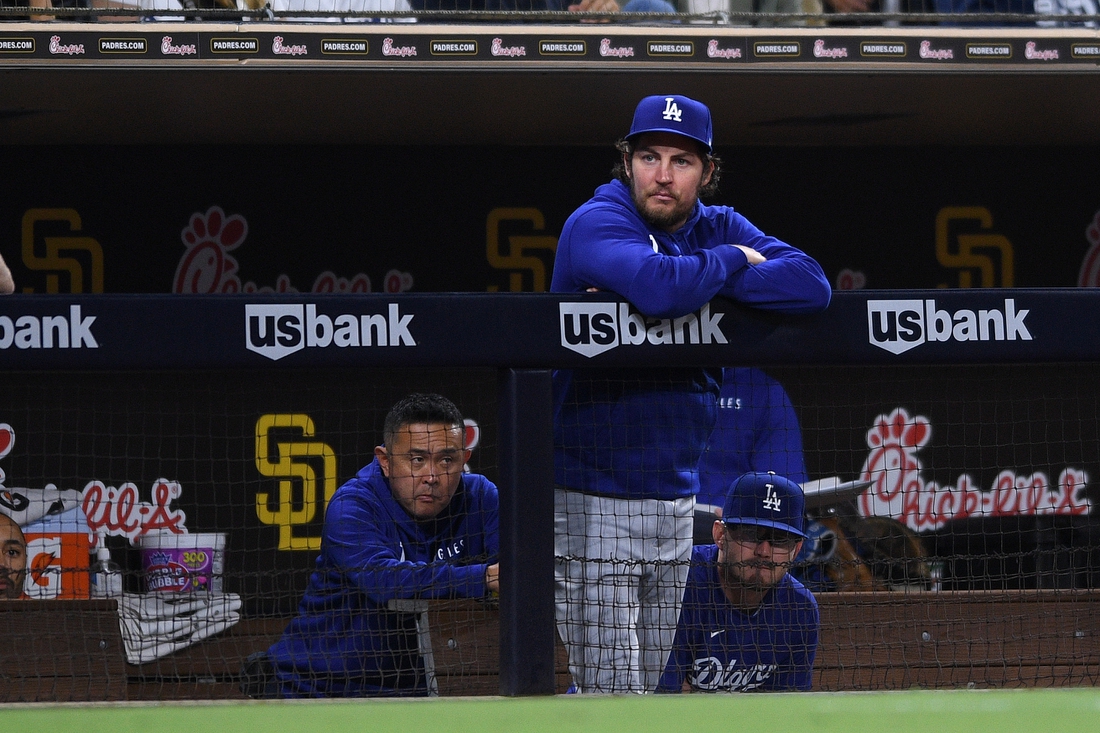 Jun 22, 2021; San Diego, California, USA; Los Angeles Dodgers starting pitcher Trevor Bauer (top) looks on from the dugout during the fifth inning against the San Diego Padres at Petco Park. Mandatory Credit: Orlando Ramirez-USA TODAY Sports