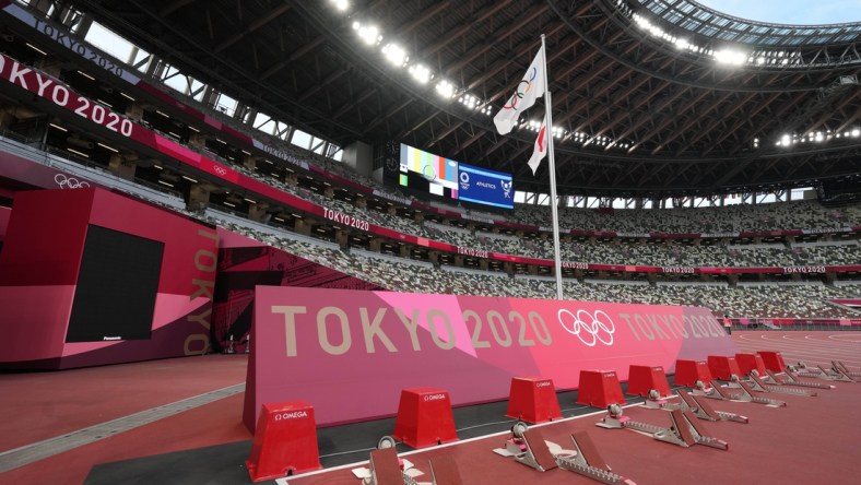 Jul 29, 2021; Tokyo, Japan; A general overall view of the starting blocks on the track and Olympic rings and Japan flags at New National Stadium, the venue for track and field and opening and closing ceremonies during the Tokyo 2020 Olympic Summer Games. Mandatory Credit: Kirby Lee-USA TODAY Sports