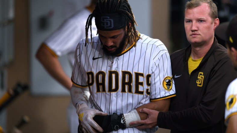 Jul 30, 2021; San Diego, California, USA; San Diego Padres shortstop Fernando Tatis Jr. (left) is helped through the dugout by a trainer after sustaining an injury during the first inning against the Colorado Rockies at Petco Park. Mandatory Credit: Orlando Ramirez-USA TODAY Sports