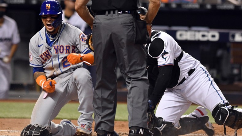 Aug 4, 2021; Miami, Florida, USA; New York Mets shortstop Javier Baez (23) celebrates after scoring a run against Miami Marlins catcher Alex Jackson (right) during the second inning at loanDepot Park. Mandatory Credit: Jim Rassol-USA TODAY Sports