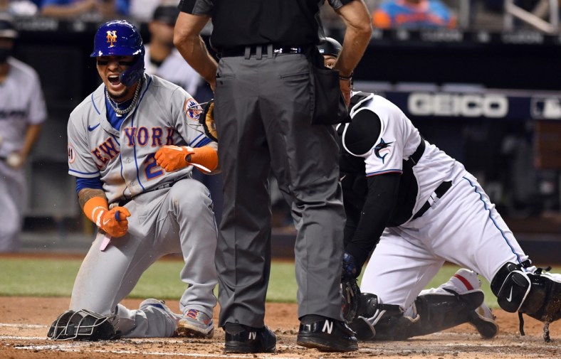 Aug 4, 2021; Miami, Florida, USA; New York Mets shortstop Javier Baez (23) celebrates after scoring a run against Miami Marlins catcher Alex Jackson (right) during the second inning at loanDepot Park. Mandatory Credit: Jim Rassol-USA TODAY Sports