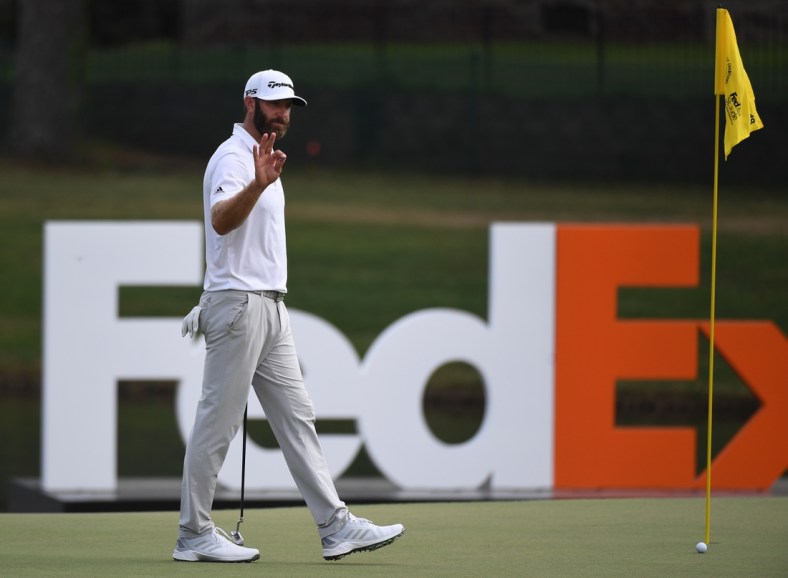 Aug 7, 2021; Memphis, Tennessee, USA; Dustin Johnson waives to the crowd as he approaches the 18th green during the third round of the WGC FedEx St. Jude Invitational golf tournament at TPC Southwind. Mandatory Credit: Christopher Hanewinckel-USA TODAY Sports