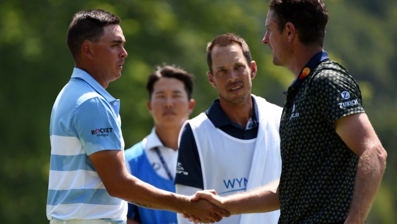 Aug 13, 2021; Greensboro, North Carolina, USA; Justin Rose (far right) shakes hands with Rickie Fowler after completing  the second round of the Wyndham Championship golf tournament. Mandatory Credit: Rob Kinnan-USA TODAY Sports