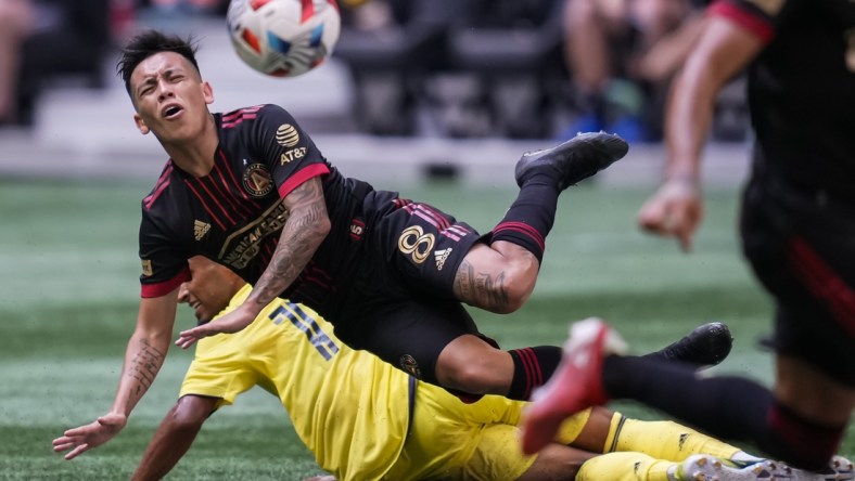 Aug 28, 2021; Atlanta, Georgia, USA; Atlanta United midfielder Ezequiel Barco (8) flies over Nashville SC midfielder Hany Mukhtar (10) after playing the ball during the first half at Mercedes-Benz Stadium. Mandatory Credit: Dale Zanine-USA TODAY Sports