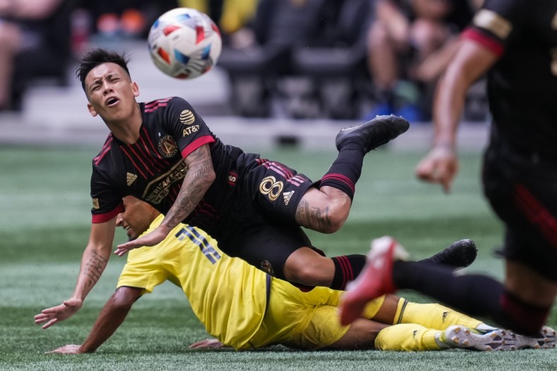 Aug 28, 2021; Atlanta, Georgia, USA; Atlanta United midfielder Ezequiel Barco (8) flies over Nashville SC midfielder Hany Mukhtar (10) after playing the ball during the first half at Mercedes-Benz Stadium. Mandatory Credit: Dale Zanine-USA TODAY Sports