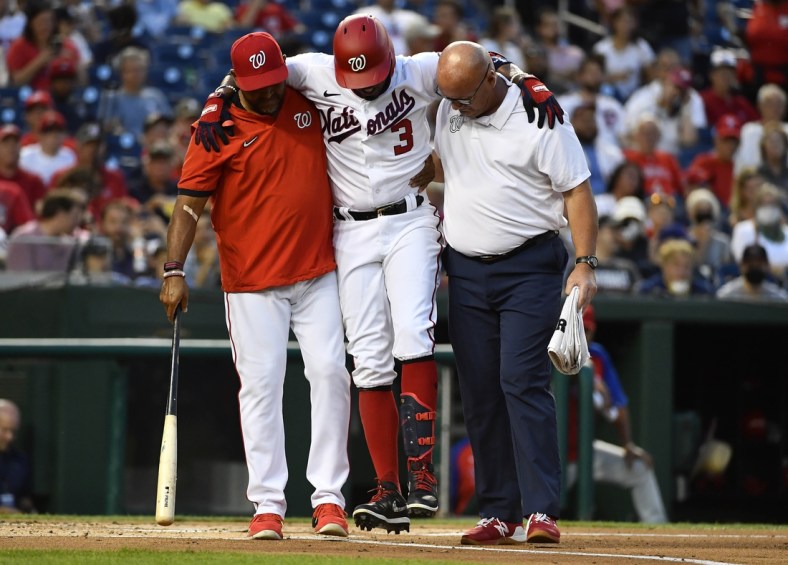 Aug 30, 2021; Washington, District of Columbia, USA; Washington Nationals shortstop Alcides Escobar (3) is helped off the field by manager Dave Martinez (left) after fouling a ball off his leg against the Philadelphia Phillies during the first inning at Nationals Park. Mandatory Credit: Brad Mills-USA TODAY Sports