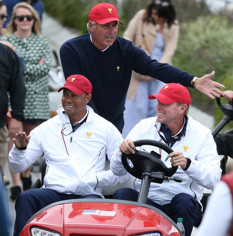 Sep 30, 2017; Jersey City, NJ, USA; (From left) Assistant captains to the U.S. team Tiger Woods and Fred Couples and Captain of the U.S. team Steve Stricker greet fans while riding in a cart during the third round foursomes matches of The President's Cup golf tournament at Liberty National Golf Course. Mandatory Credit: Bill Streicher-USA TODAY Sports