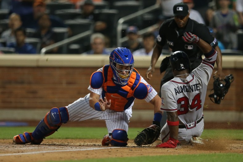 Jul 28, 2021; New York City, New York, USA; New York Mets catcher James McCann (33) tags out Atlanta Braves left fielder Abraham Almonte (34) trying to score on a hit by Atlanta Braves pinch hitter Ehire Adrianza (not pictured) during the ninth inning at Citi Field. Mandatory Credit: Brad Penner-USA TODAY Sports