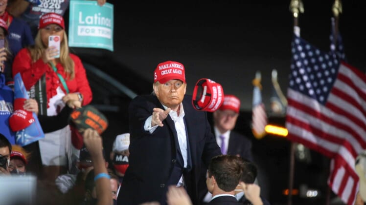 U.S. President Donald Trump tosses a Make America Great Again hat into a crowd of thousands after speaking at the Des Moines International Airport during a rally in Iowa on Wednesday, Oct. 14, 2020.20201014 Trumpiowa