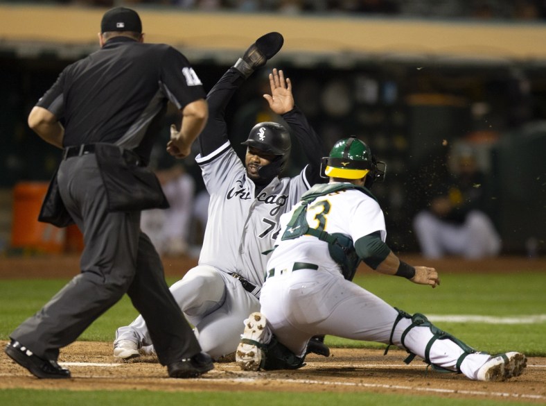 Sep 7, 2021; Oakland, California, USA; Chicago White Sox left fielder Eloy Jimenez (74) scores ahead of the tag by Oakland Athletics catcher Yan Gomes (23) on a single by Gavin Sheets during the fifth inning at RingCentral Coliseum. Umpire is Jeremy Riggs. Mandatory Credit: D. Ross Cameron-USA TODAY Sports