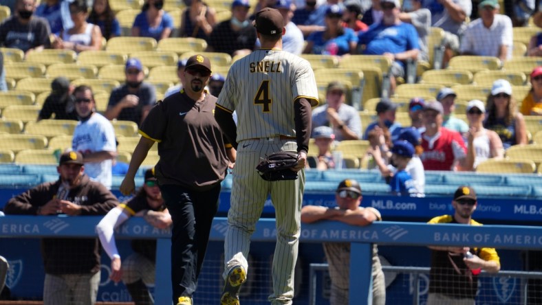 Sep 12, 2021; Los Angeles, California, USA; San Diego Padres trainer walks out of the dugout to meet San Diego Padres starting pitcher Blake Snell (4) after Snell injured himself throwing a pitch in the first inning against the Los Angeles Dodgers at Dodger Stadium. Mandatory Credit: Robert Hanashiro-USA TODAY Sports