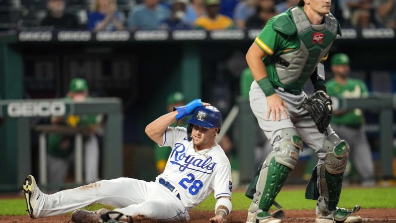 Sep 14, 2021; Kansas City, Missouri, USA; Kansas City Royals center fielder Kyle Isbel (28) slides into home plate to score as Oakland Athletics catcher Sean Murphy (12) awaits the throw during the third inning at Kauffman Stadium. Mandatory Credit: Jay Biggerstaff-USA TODAY Sports